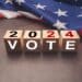 United States presidential election in 2024. Wooden cubes with text VOTE and 2024 over the American flag background. Politics and voting conceptual